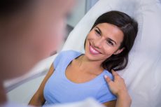 Female patient smiling while talking to doctor at clinic